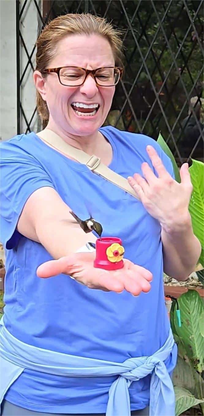 Feeding a Hummingbird in Mindo, Ecuador Woman in a blue shirt smiling with