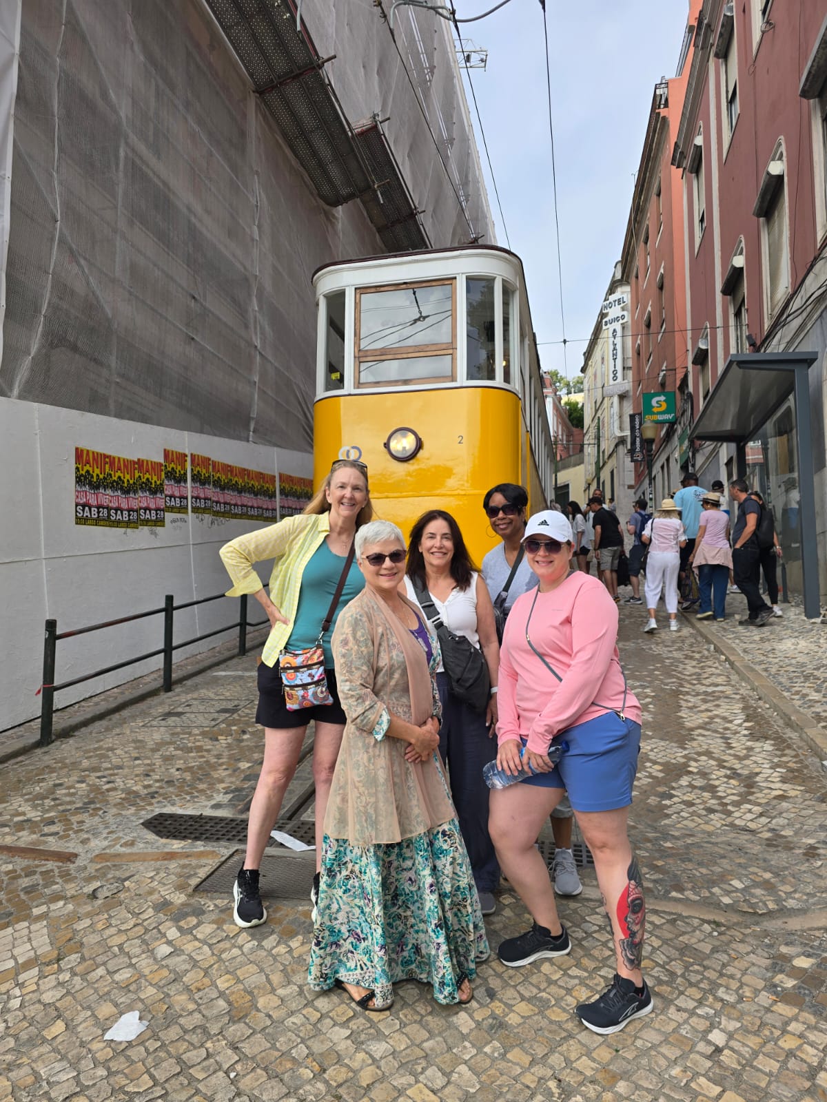 adabcd67-9b7c-403a-8f06-0c7fa50c16d4 Colorful tram climbing Lisbon’s Alfama neighborhood with azuejo-tiled buildings