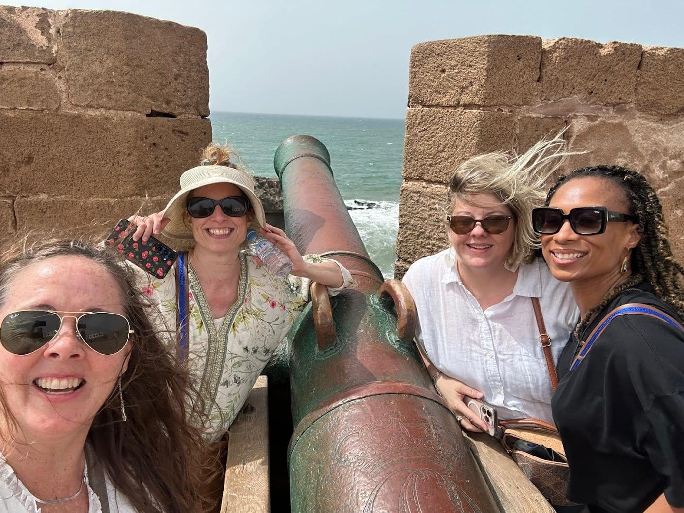 Women travelers smiling together on a sunny coastal path in Morocco WTA travelers smiling together on a sunny coastal path in Morocco