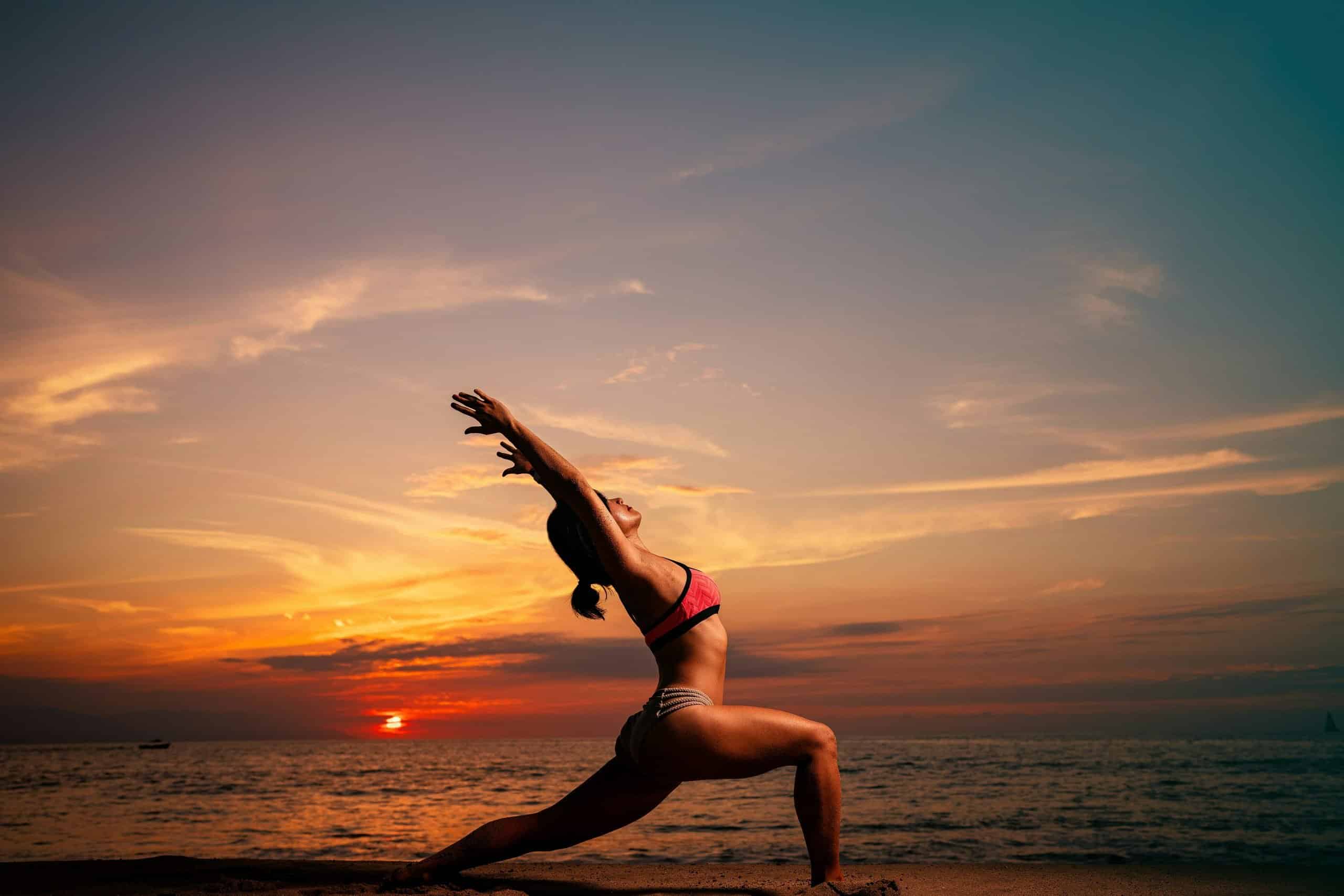 Woman practicing yoga at sunrise on a tropical beach in Southeast Asia Woman practicing yoga at sunrise on a tropical beach in Southeast Asia