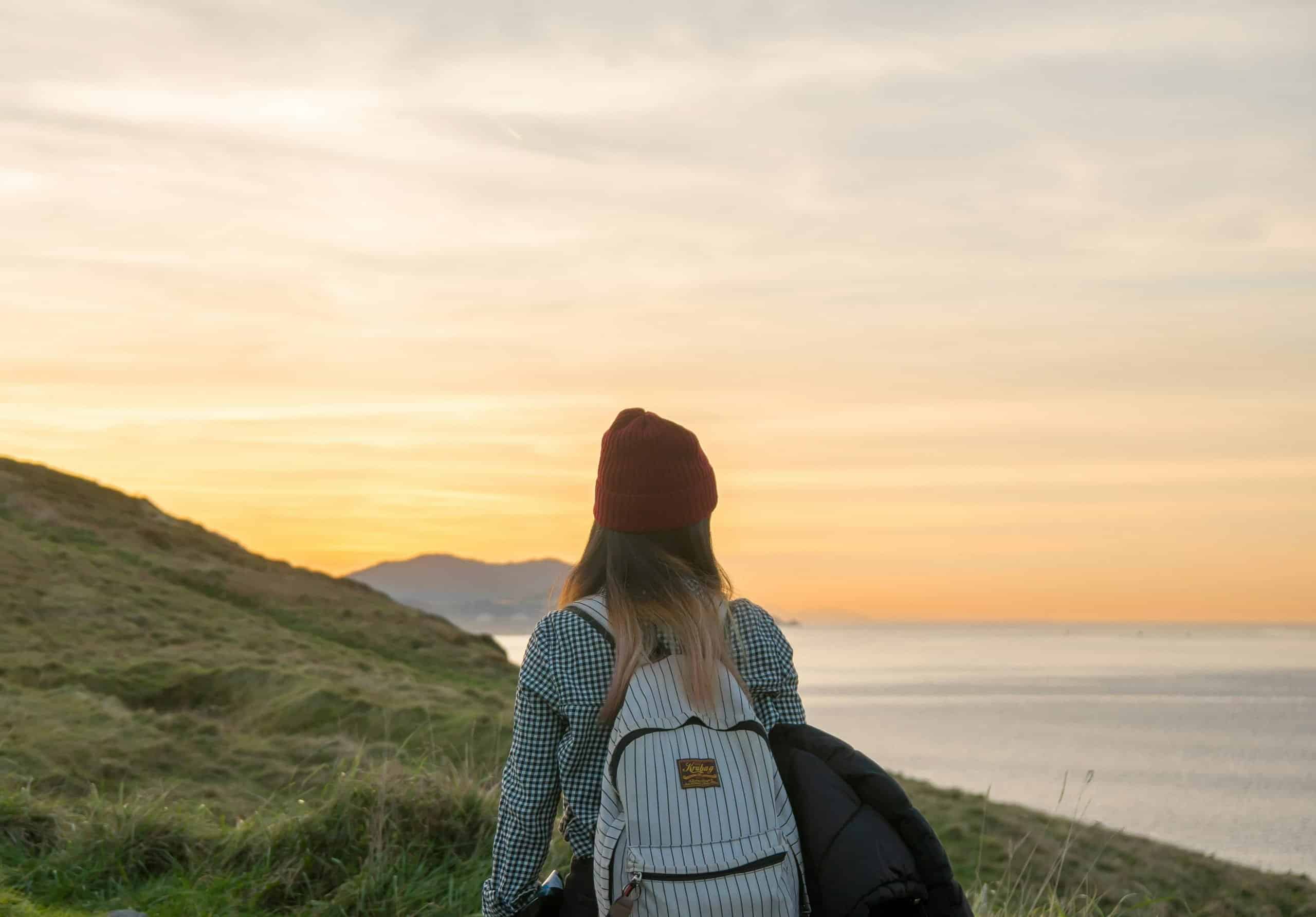 Solo female traveler with a backpack overlooking a stunning landscape Solo female traveler with a backpack overlooking a stunning landscape