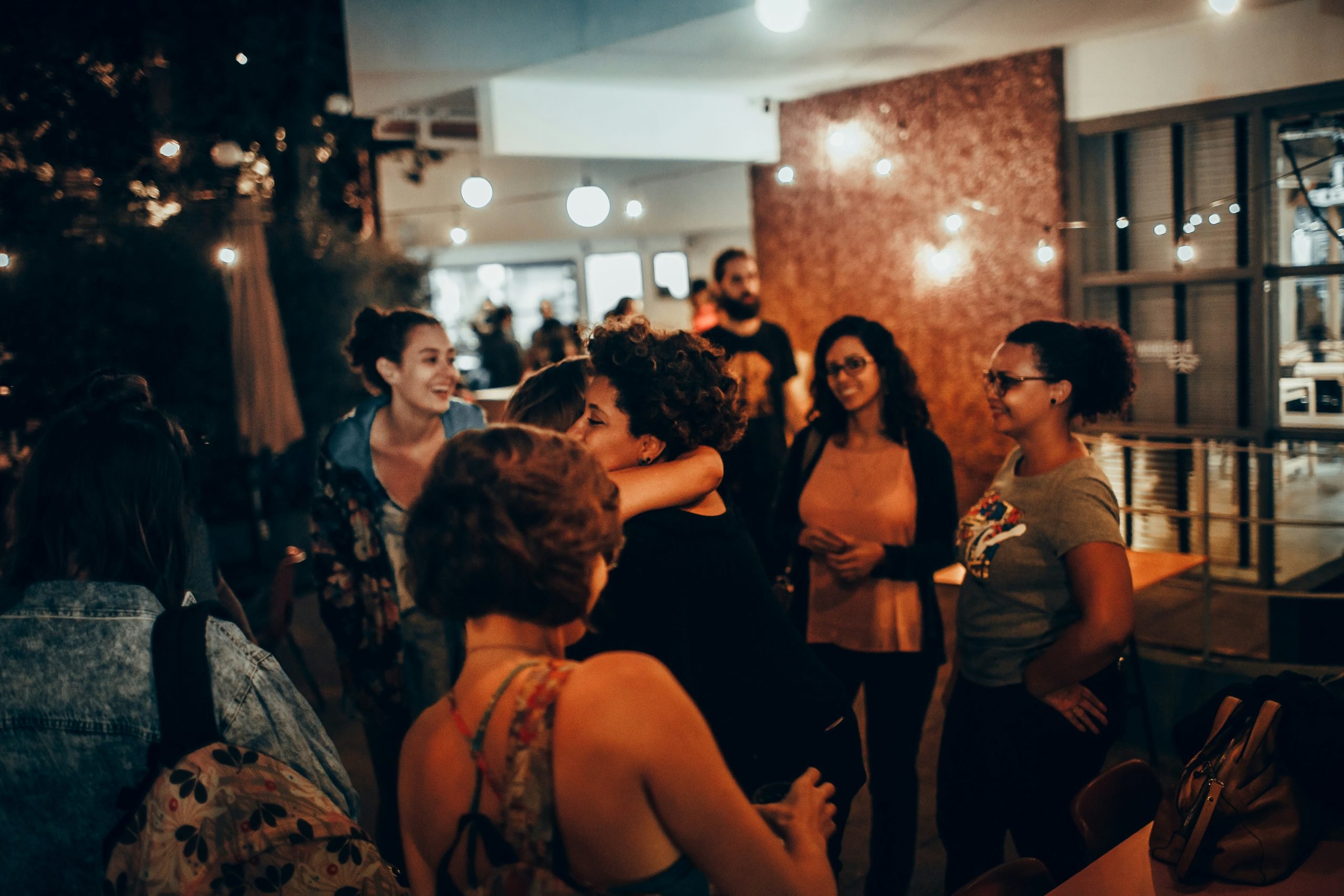 A candid image of women meeting for the first time in a boutique hotel courtyard, greeting each other with smiles and hugs A candid image of women meeting for the first time in a boutique hotel courtyard, greeting each other with smiles and hugs