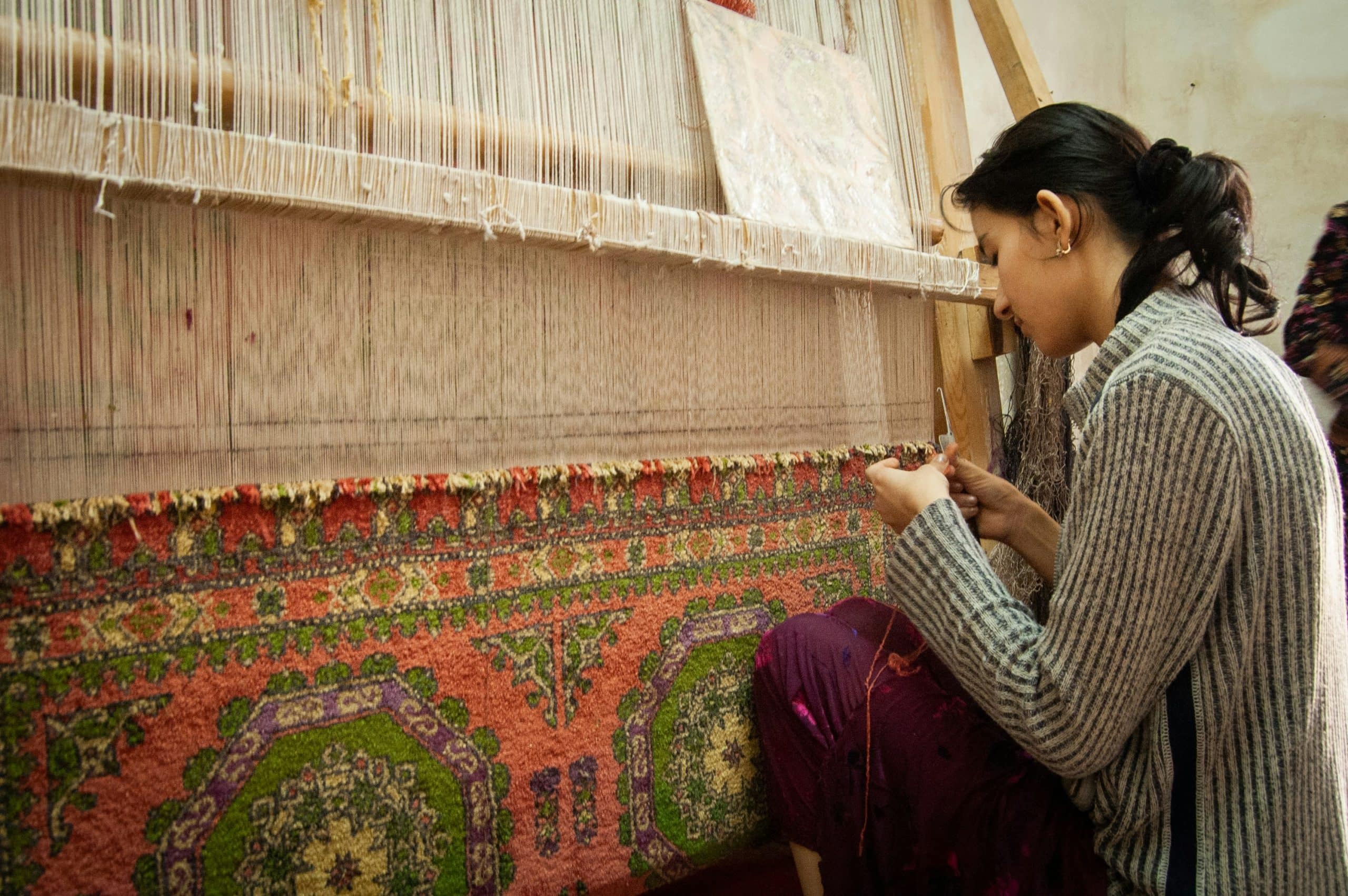 Berber woman weaving a traditional Moroccan carpet using a handloom in a women's cooperative in the Atlas Mountains. The Westfjords