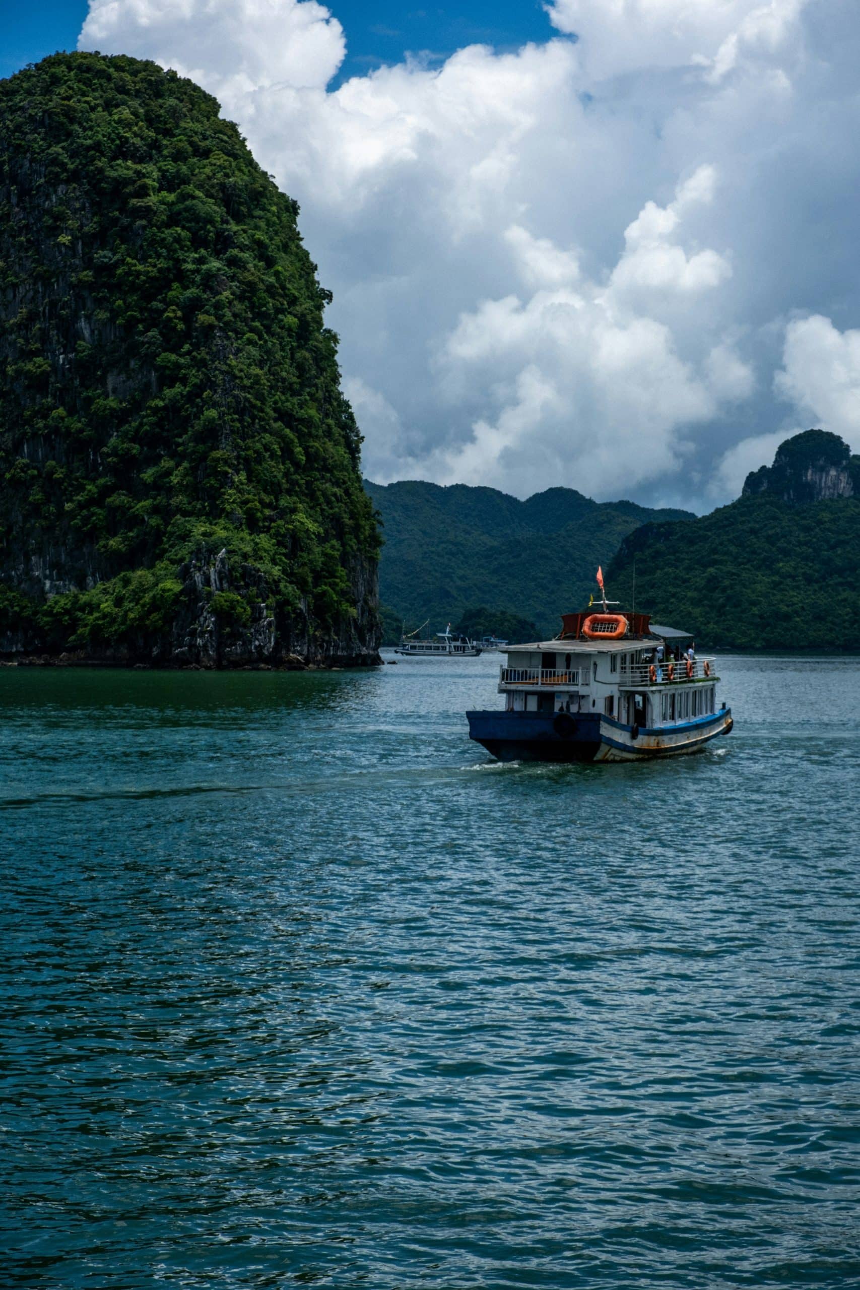 A solo traveler cruising through Halong Bay surrounded by misty limestone karsts A solo traveler cruising through Halong Bay surrounded by misty limestone karsts