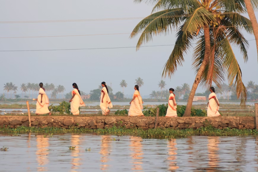  serene scene of several women dressed in traditional white sarees in Kerala