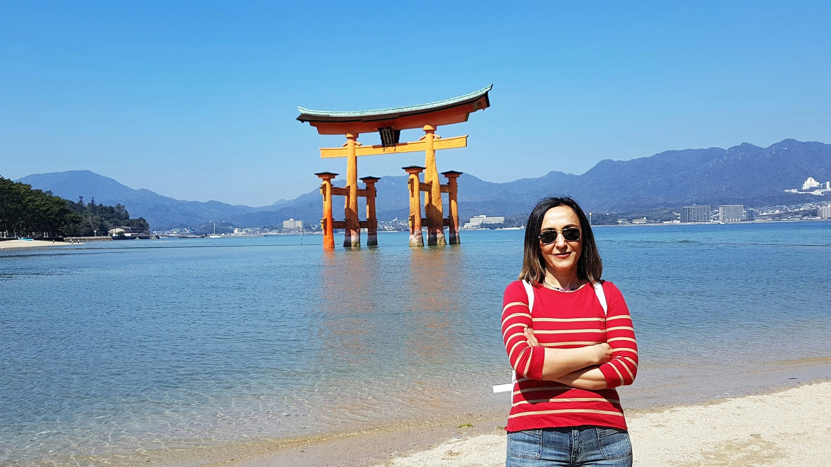 A lone woman standing in front of the torii gate of Miyajima Island